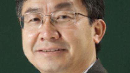 headshot of Asian male with eyeglasses wearing a dark suit and tie