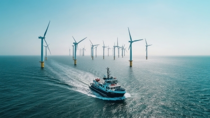 A boat navigates through an offshore wind farm with turbines in the background.