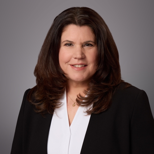 Headshot of female with long dark brown hair wearing a shite blouse and a black jacket.