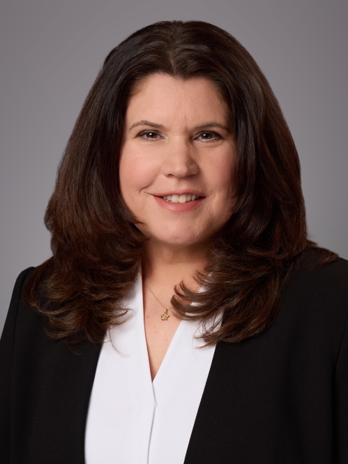 Headshot of female with long dark brown hair wearing a shite blouse and a black jacket.