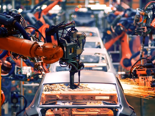 Automotive factory setting with orange robotic arms.